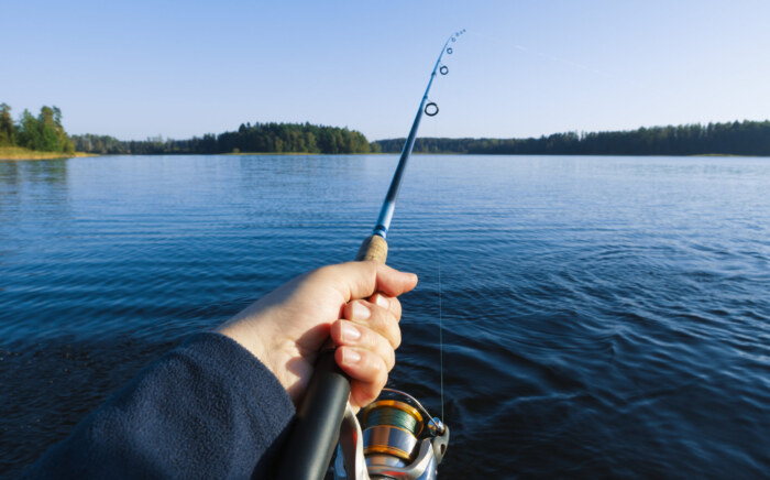 Fishing on a lake at sunset. Fishing rod with a reel in hand.