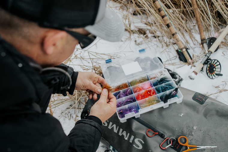 angler selecting a fly from a tackle box to target steelhead