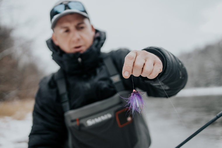 angler holding a fly to target steelhead