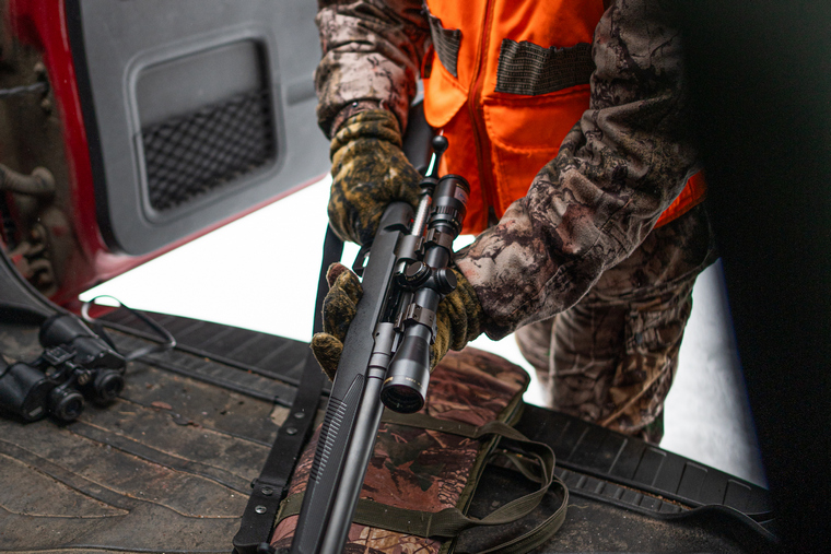 hunter retrieving rifle from vehicle