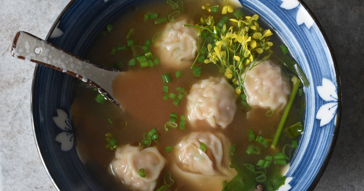 A bowl of soup with delicate moose meat wontons floating in flavorful broth and green onions