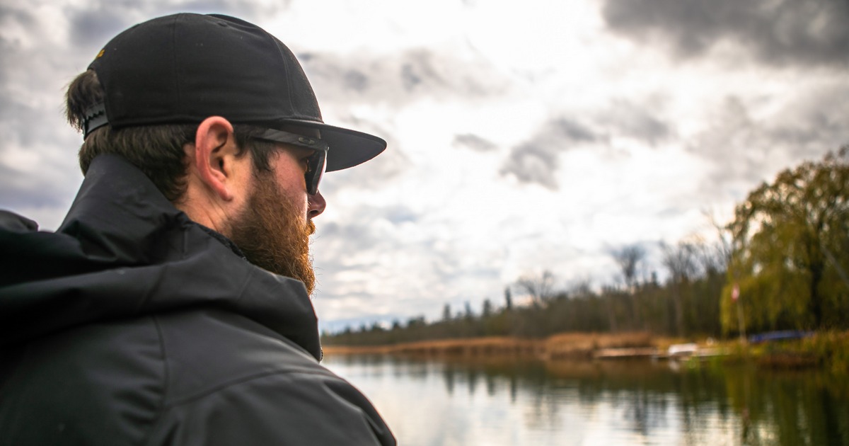 An angler gazes into the distance while fishing, rod in hand.