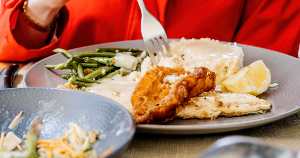 Crispy golden fried fish fillets on a plate, served with lemon wedges and a side of vegtables.