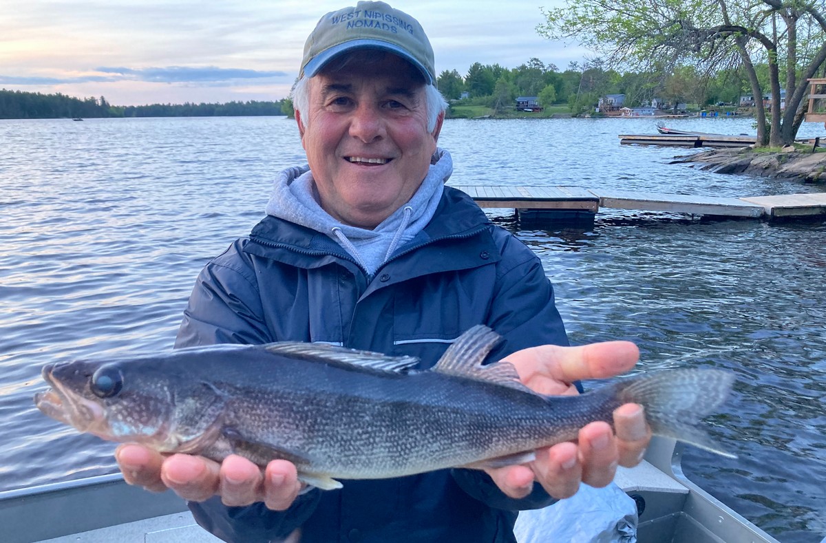 Fisherman (frank cecchini) extends his arms to display a rare blue walleye.