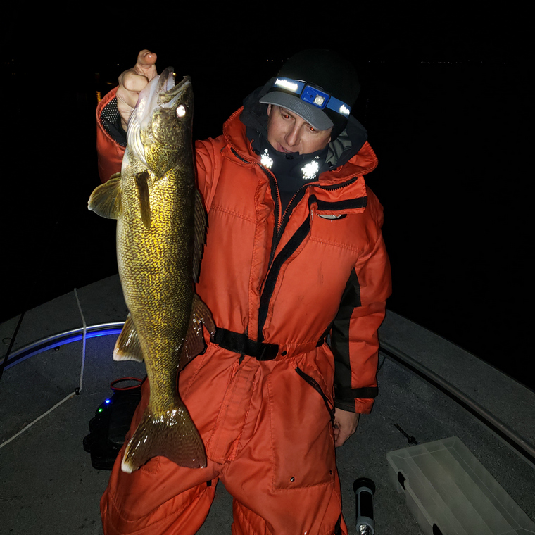 Angler holding a walleye in the dark