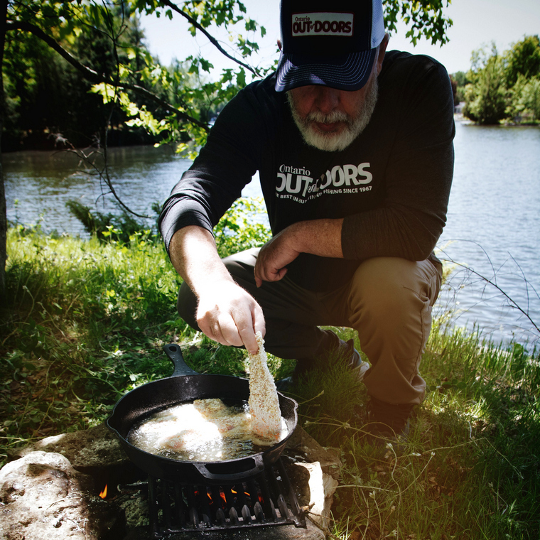 angler preparing a shore lunch over a fire