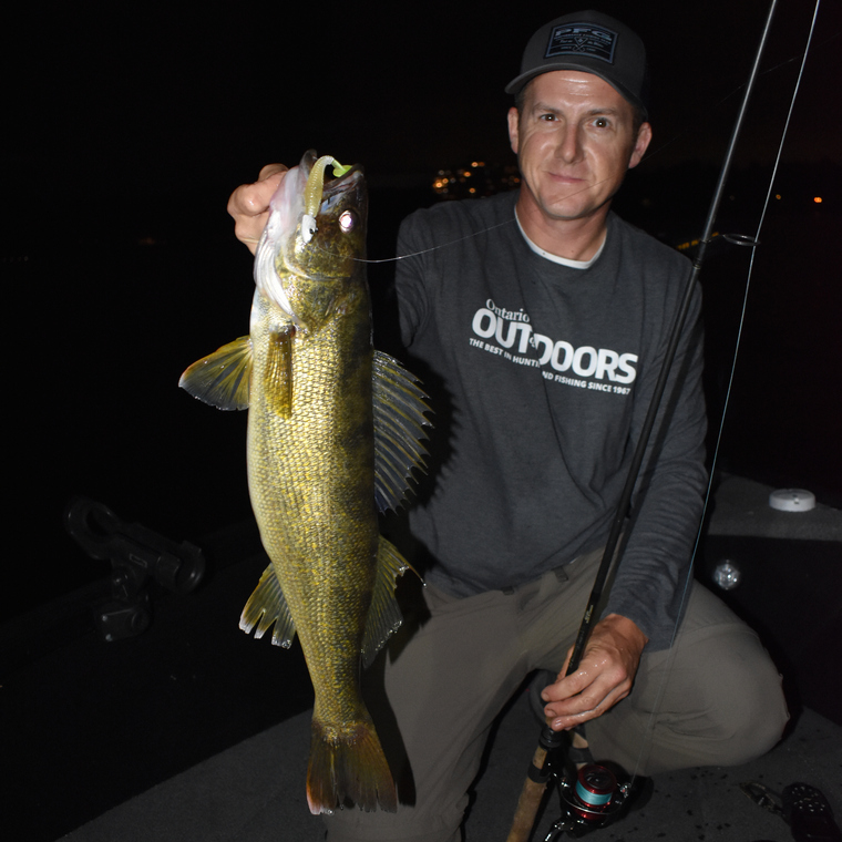 Angler holding a walleye in the dark